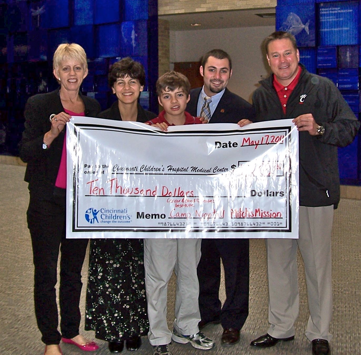 Local foundation, Mitch's Mission, presented a check for $10,000 to Cincinnati Children's. On hand were Dee Stone, Dr. Mariam Fouladi, an oncologist at Children's, Mitch Stone, Drew Smith, UC Student body President, and Butch Jones, UC Head Football coach.